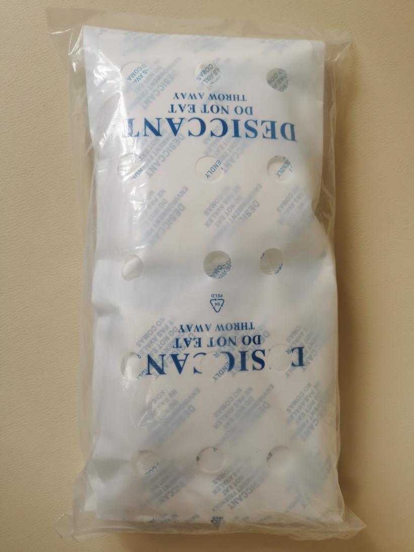 Detail of a white container desiccant bag showing six ventilation holes and the reinforced hook tab